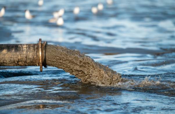 Pipe discharging polluted wastewater into a river, illustrating the effects of sewage water pollution on waterways and aquatic ecosystems.
