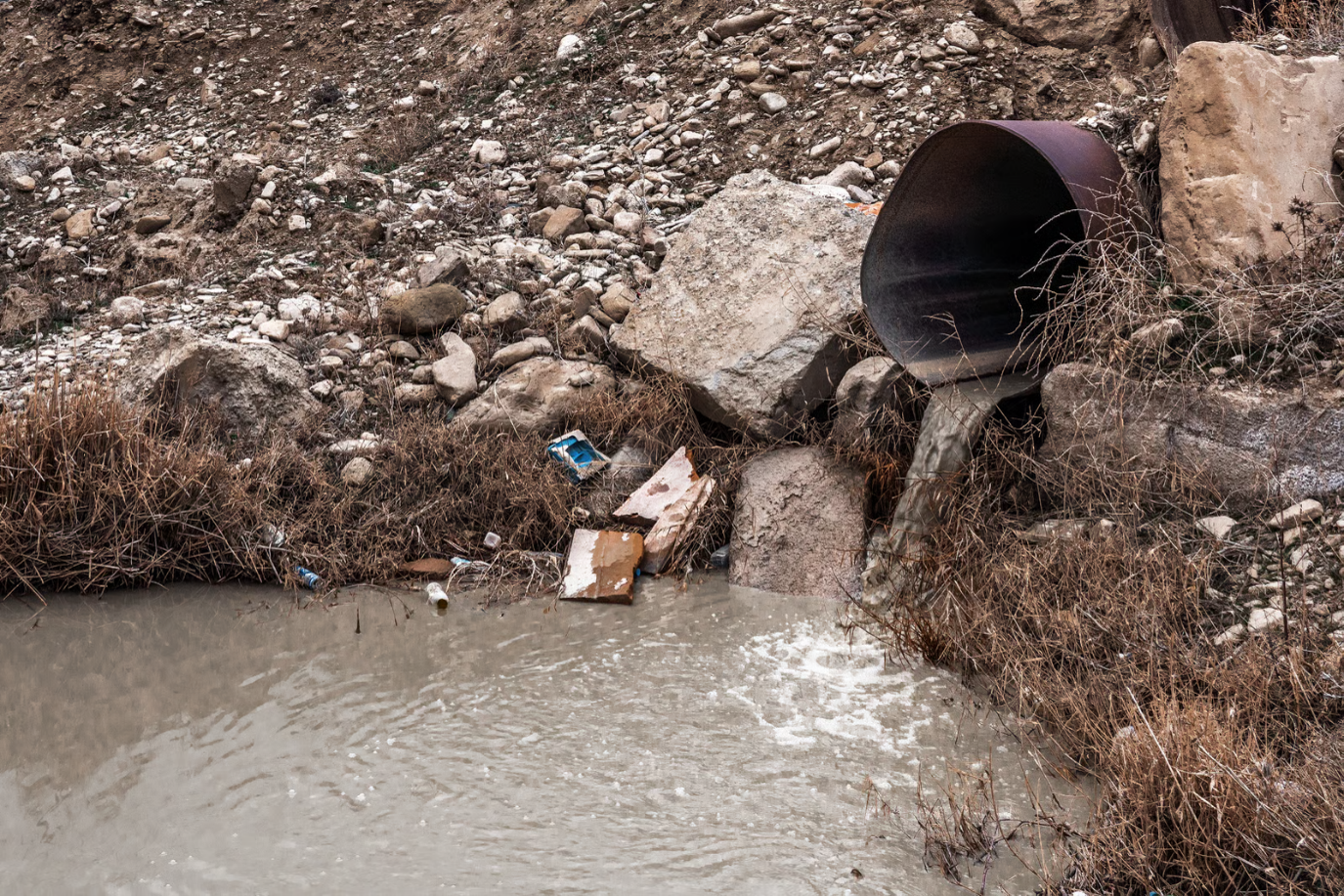 Wastewater discharging from a pipe into a waterway, representing sewage water pollution and its environmental impact.